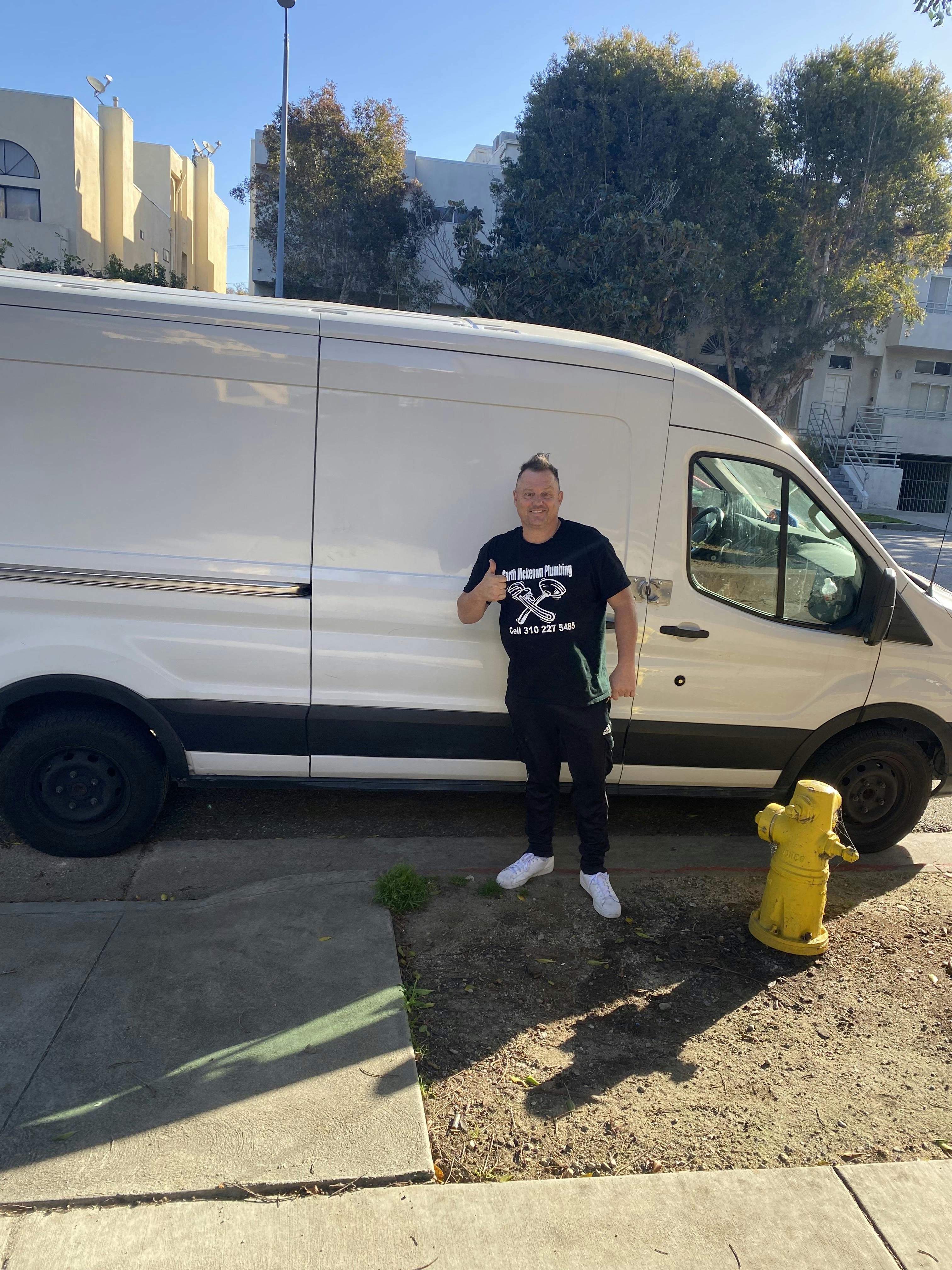 picture of a plumber standing outside his work van 